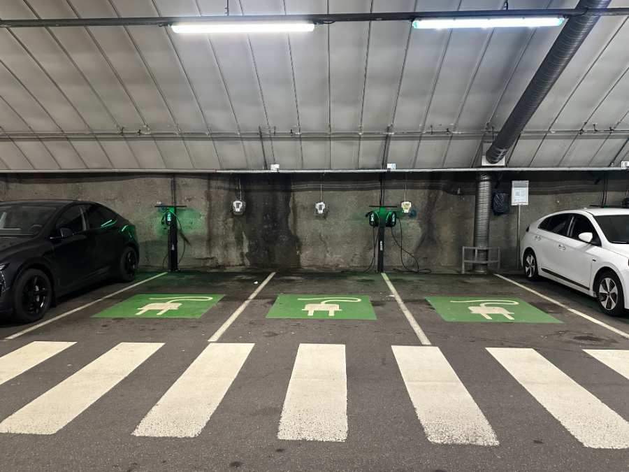Parkdeck mit drei grün markierten Stellplätzen, dahinter Wallboxen an Wand und Pfosten