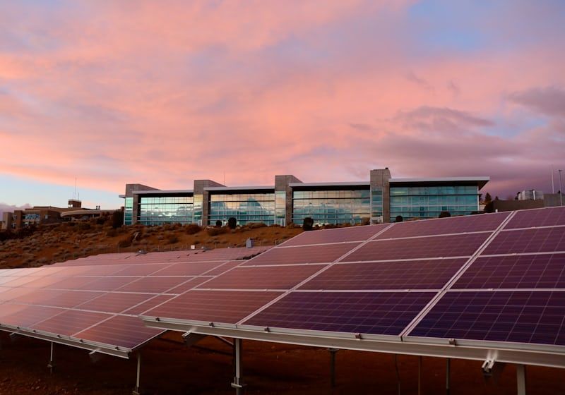 Photovoltaikmodule vor einem Bürogebäude in der Abenddämmerung