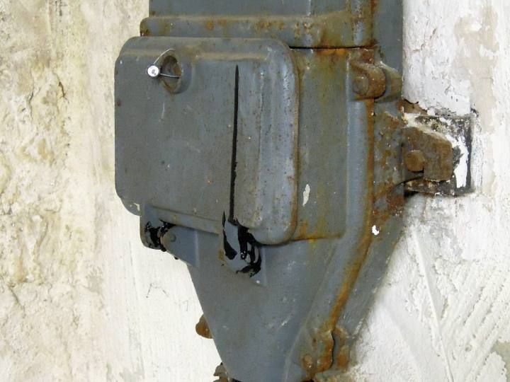 Alter Hausanschlusskasten aus Gusseisen an einer Kellerwand