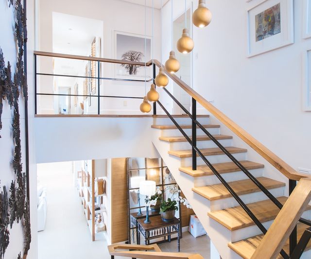 Treppenhaus am Abend, warme Pendelleuchten hängen über der Holztreppe