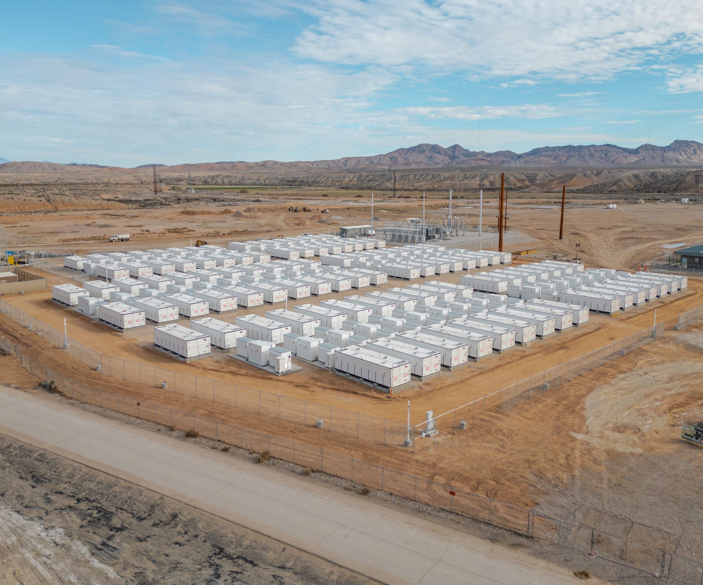 Reihen weißer Batteriecontainer eines großen Speichers auf einem eingezäunten Gelände
