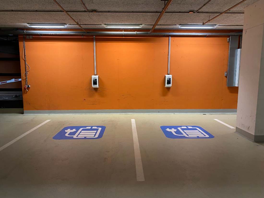 Zwei Wallboxen an der Wand einer Tiefgarage über markierten Stellplätzen